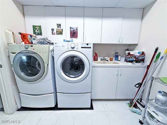 laundry area featuring sink, washing machine and dryer, cabinets, and light tile patterned flooring