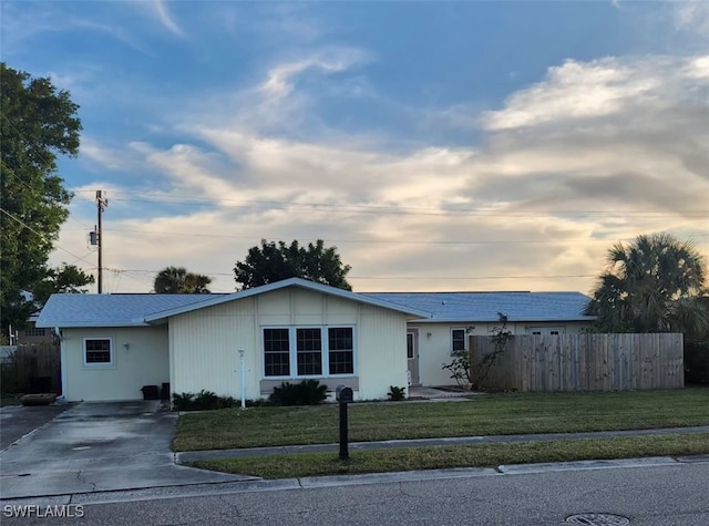 ranch-style home featuring a front lawn and fence