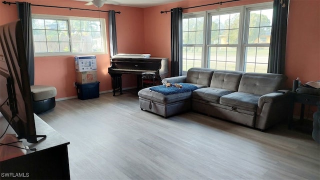 living area featuring plenty of natural light, wood finished floors, baseboards, and ceiling fan