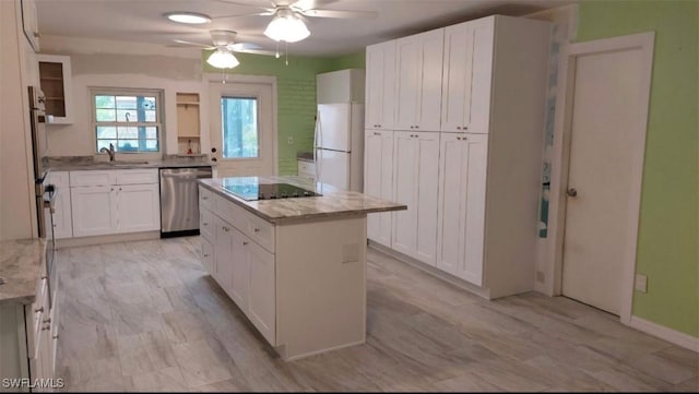 kitchen featuring stainless steel dishwasher, white fridge, white cabinetry, and a center island