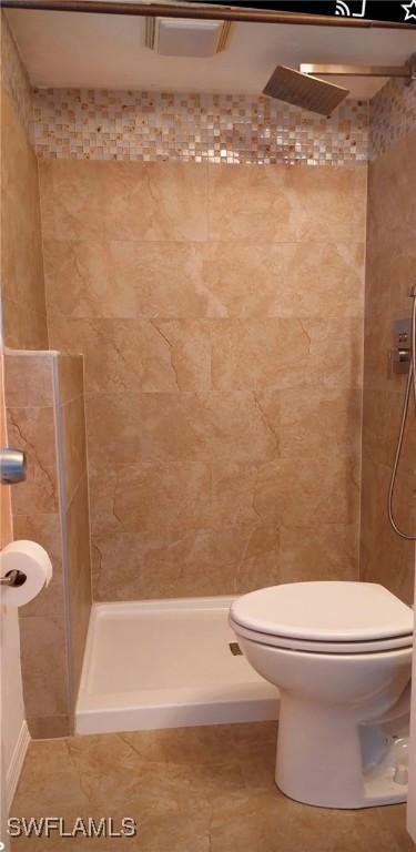 bathroom with a tile shower and toilet