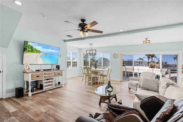 living room featuring ceiling fan with notable chandelier and light hardwood / wood-style floors