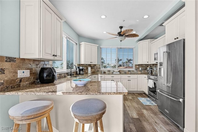 kitchen featuring sink, a kitchen breakfast bar, kitchen peninsula, stainless steel appliances, and white cabinets