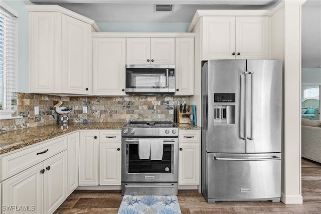 kitchen with stainless steel appliances, dark hardwood / wood-style flooring, dark stone counters, and white cabinets