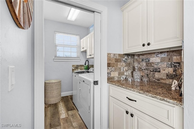 laundry area with cabinets, washing machine and clothes dryer, and dark hardwood / wood-style flooring