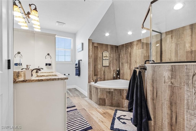 bathroom with wood-type flooring, separate shower and tub, vanity, and wood walls