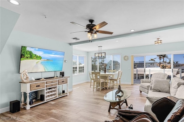 living room featuring plenty of natural light, ceiling fan with notable chandelier, and light hardwood / wood-style flooring