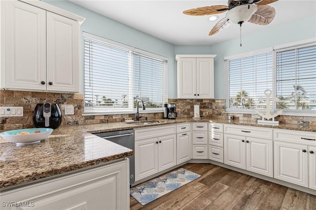 kitchen with dark stone counters, dishwasher, sink, and white cabinets