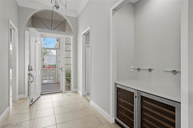 foyer entrance with wine cooler, ornamental molding, and light tile patterned floors