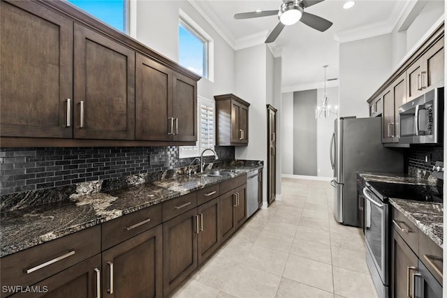 kitchen with crown molding, appliances with stainless steel finishes, dark stone countertops, and dark brown cabinetry