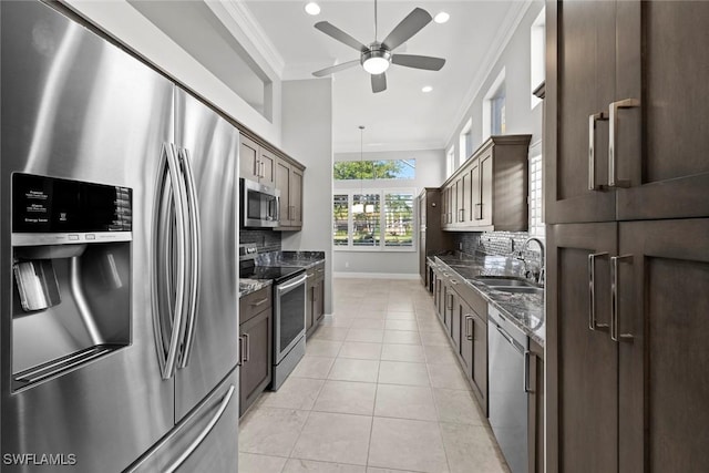 kitchen with light tile patterned flooring, sink, dark stone counters, ornamental molding, and stainless steel appliances