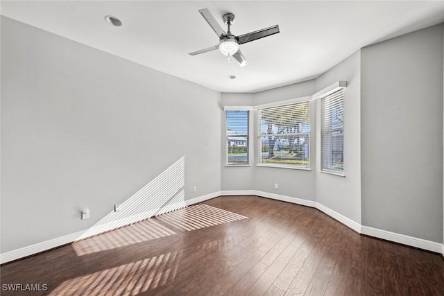 empty room with ceiling fan and dark hardwood / wood-style flooring