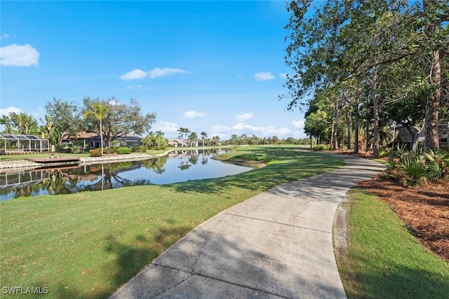 view of property's community with a water view and a lawn