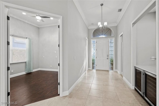 foyer entrance with ornamental molding, plenty of natural light, ceiling fan with notable chandelier, and light tile patterned floors