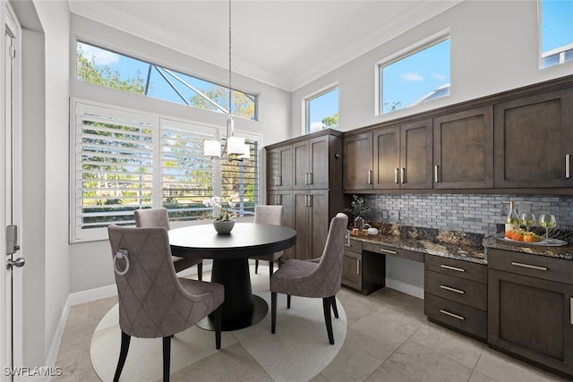 dining room featuring a high ceiling, crown molding, built in desk, and an inviting chandelier