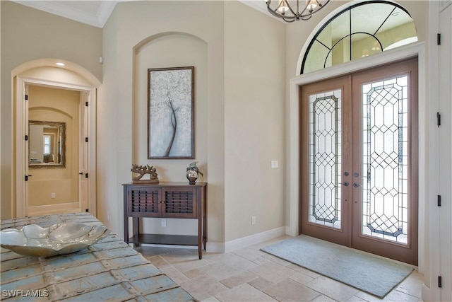 entrance foyer with an inviting chandelier, crown molding, and french doors