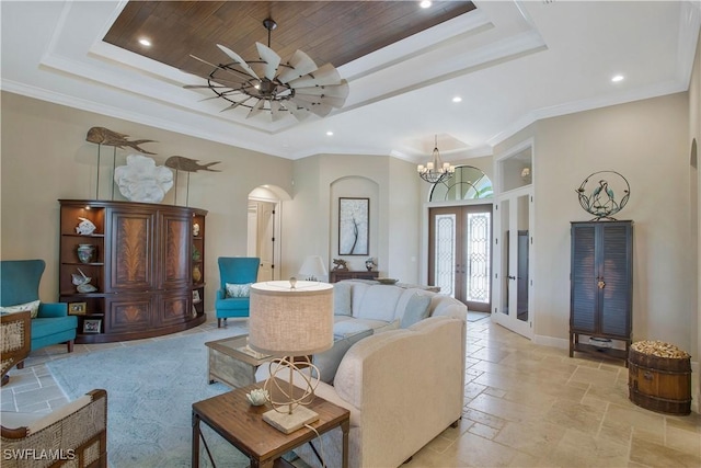 living room with french doors, ornamental molding, a raised ceiling, a notable chandelier, and a high ceiling