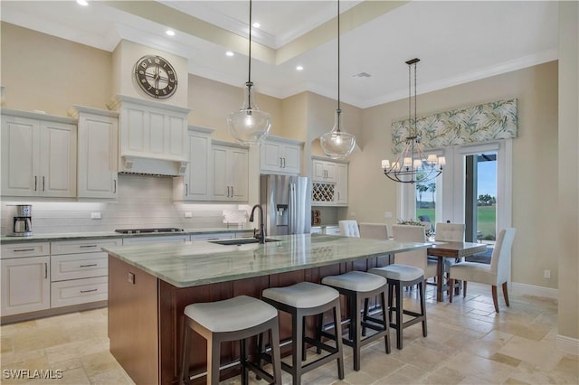 kitchen with stainless steel refrigerator with ice dispenser, white cabinets, light stone countertops, and a large island with sink