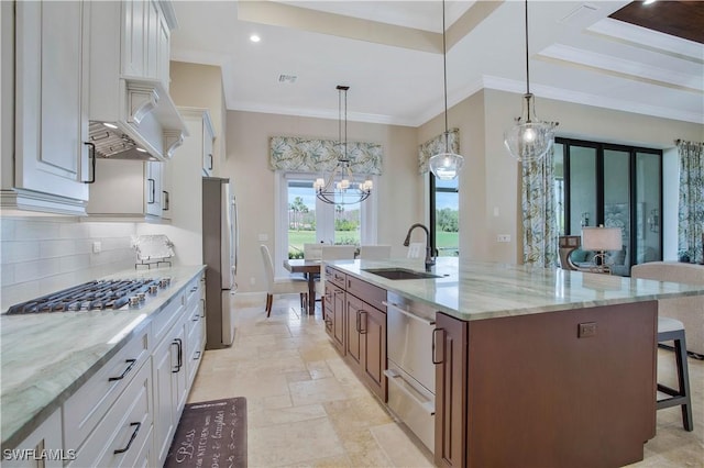 kitchen with sink, decorative light fixtures, stainless steel appliances, a kitchen island with sink, and white cabinets