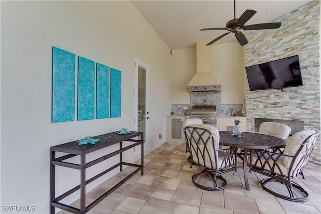 view of patio with a grill, a large fireplace, ceiling fan, and exterior kitchen