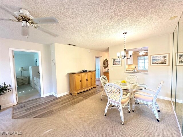 dining space featuring ceiling fan with notable chandelier, light hardwood / wood-style floors, and a textured ceiling