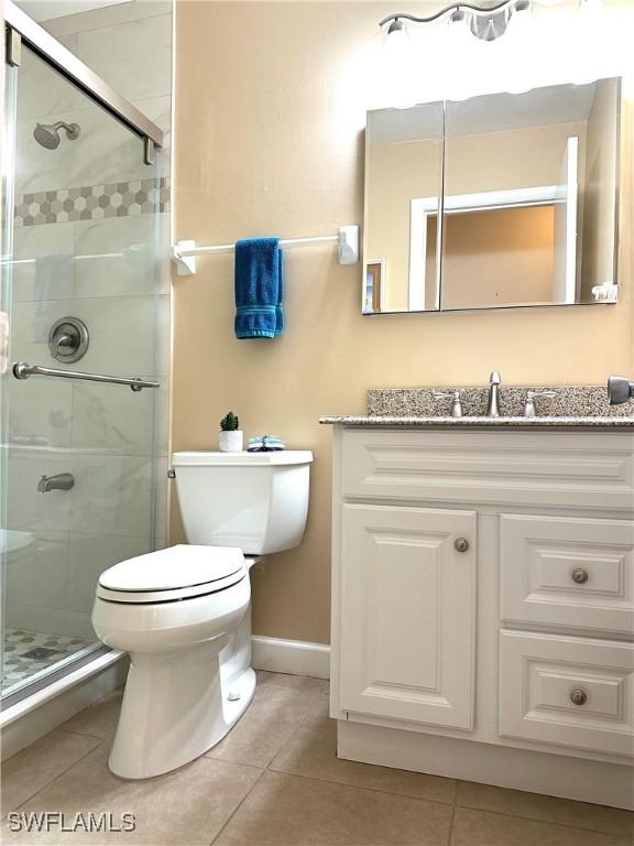 bathroom featuring vanity, tile patterned floors, toilet, and walk in shower