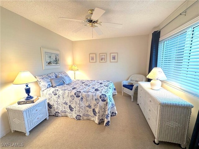 bedroom with ceiling fan, light colored carpet, and a textured ceiling