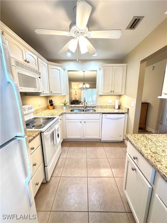 kitchen featuring sink, white appliances, light tile patterned floors, white cabinets, and ceiling fan with notable chandelier