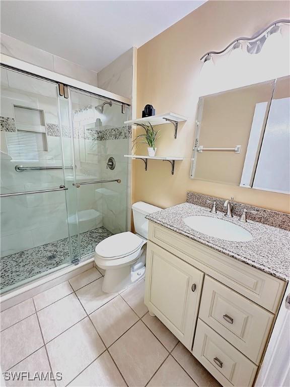 bathroom featuring vanity, tile patterned flooring, a shower with shower door, and toilet