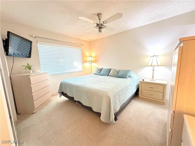 bedroom featuring ceiling fan, light carpet, and a textured ceiling