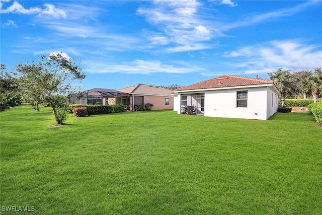 rear view of house with a yard and a lanai