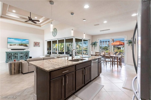 kitchen with sink, light stone counters, a center island with sink, pendant lighting, and stainless steel appliances