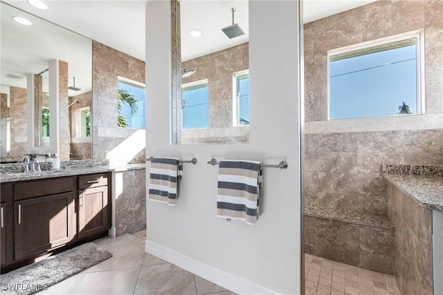 bathroom with tile patterned flooring, vanity, tiled shower, and tile walls