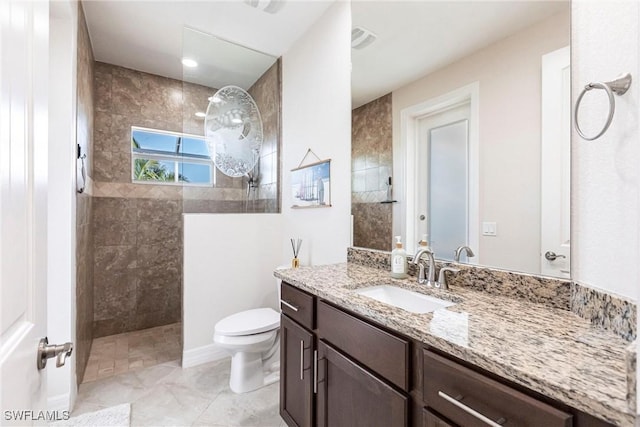 bathroom featuring tiled shower, vanity, and toilet