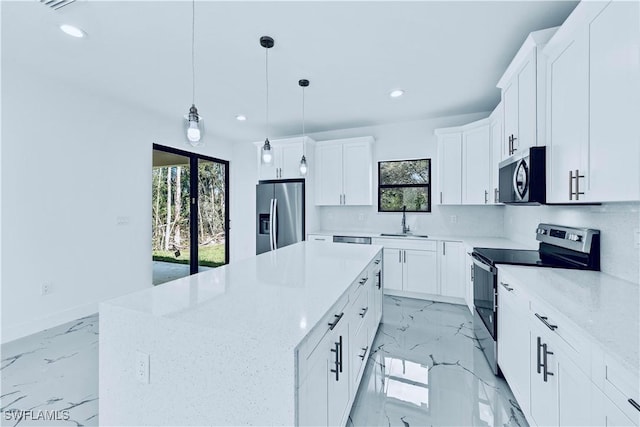 kitchen featuring white cabinetry, stainless steel appliances, light stone counters, a kitchen island, and decorative light fixtures