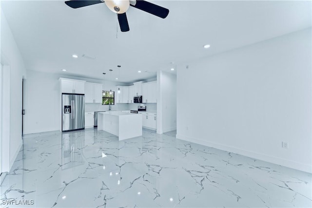 kitchen featuring ceiling fan, white cabinetry, stainless steel appliances, a center island, and decorative light fixtures