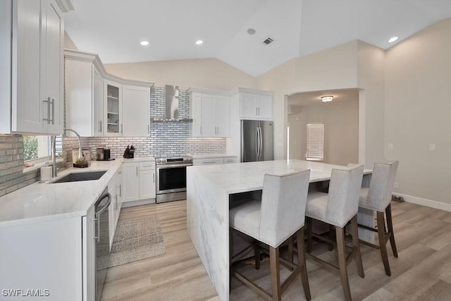 kitchen featuring stainless steel appliances, a kitchen island, sink, and white cabinets