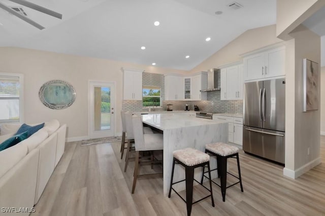 kitchen with stainless steel appliances, white cabinetry, a kitchen island, and a breakfast bar area