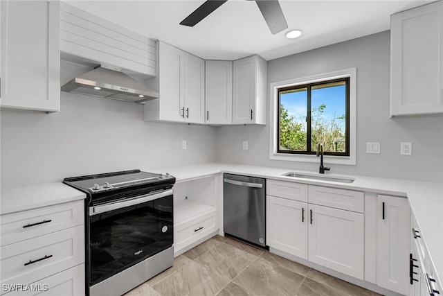 kitchen featuring wall chimney exhaust hood, white cabinetry, appliances with stainless steel finishes, and sink