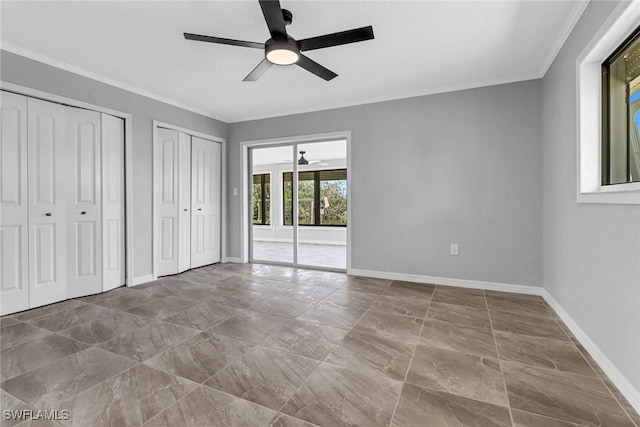 unfurnished bedroom with ceiling fan, ornamental molding, and multiple closets