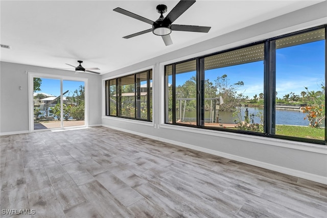 unfurnished sunroom with a water view and ceiling fan