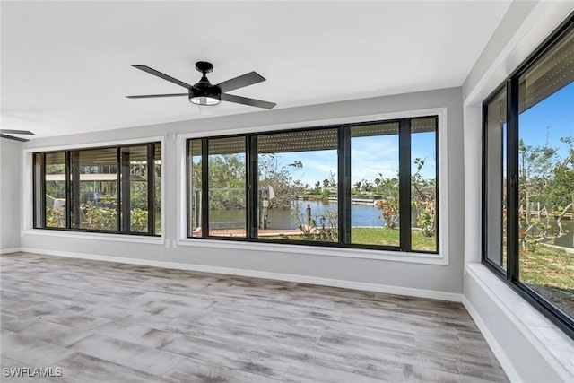 unfurnished sunroom with a water view and ceiling fan