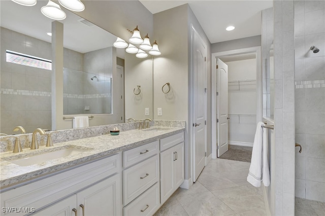 bathroom featuring tiled shower, vanity, and tile patterned flooring