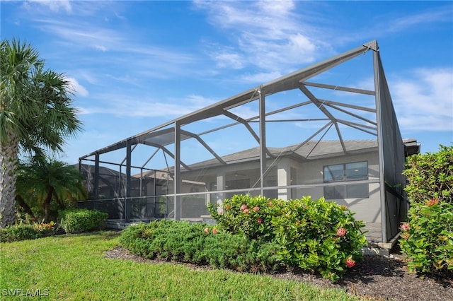 back of property featuring a yard and glass enclosure