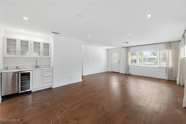 unfurnished living room with wine cooler, wet bar, and dark wood-type flooring