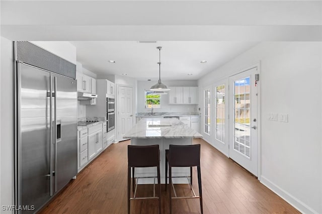 kitchen featuring hanging light fixtures, white cabinetry, appliances with stainless steel finishes, and a kitchen island