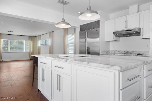 kitchen with built in refrigerator, dark hardwood / wood-style floors, pendant lighting, light stone countertops, and white cabinets