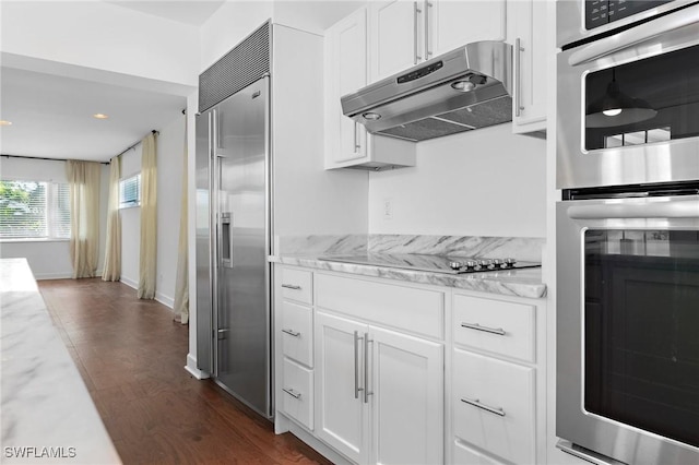 kitchen with stainless steel appliances, dark wood-type flooring, white cabinets, and light stone counters