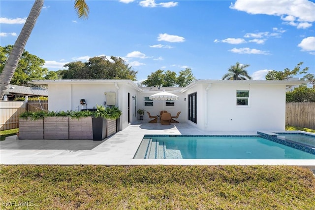 back of property featuring a pool with hot tub and a patio