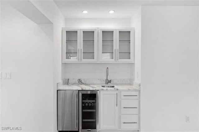 bar with white cabinetry, light stone countertops, sink, and wine cooler